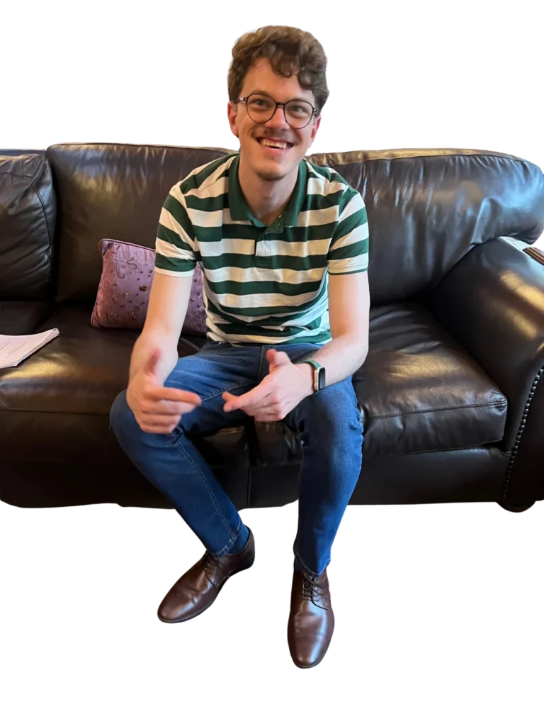 Hein Ginster smiling while seated on a sofa.